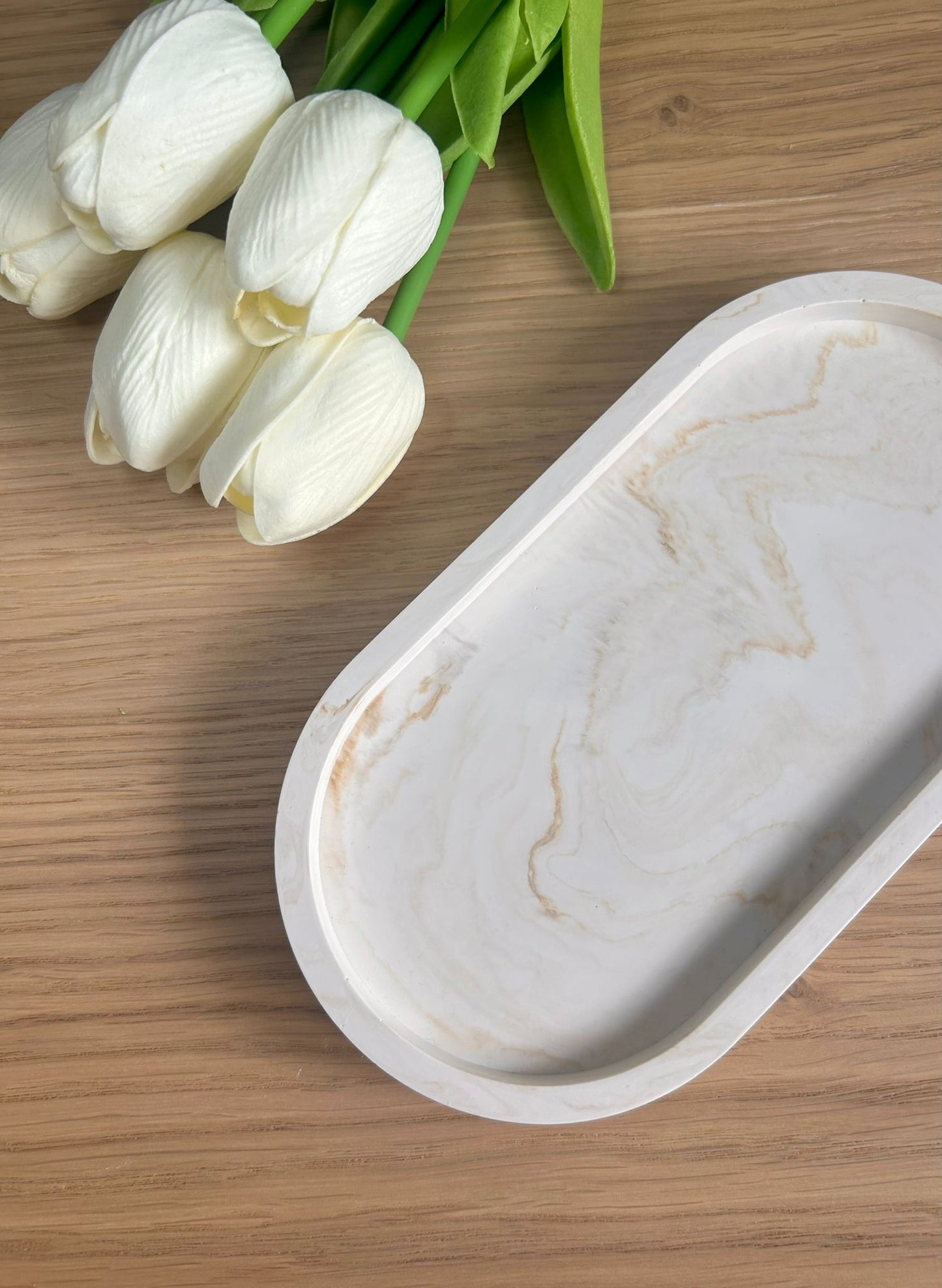 Handmade home accessory – oval Jesmonite tray with a warm marbled finish, styled with faux white tulips on a wooden surface. A beautiful display piece.