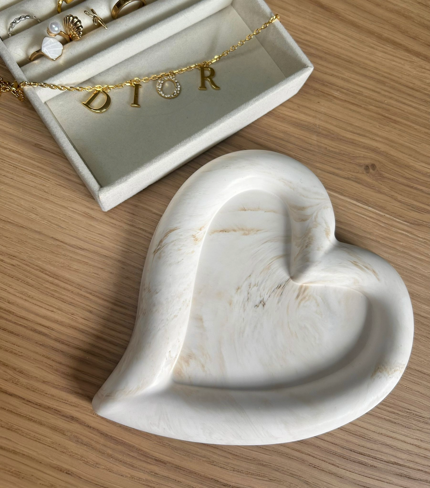 Handmade home accessory – heart-shaped Jesmonite tray with warm cream marbling, styled with a gold Dior bracelet. A minimalist jewellery dish crafted sustainably.