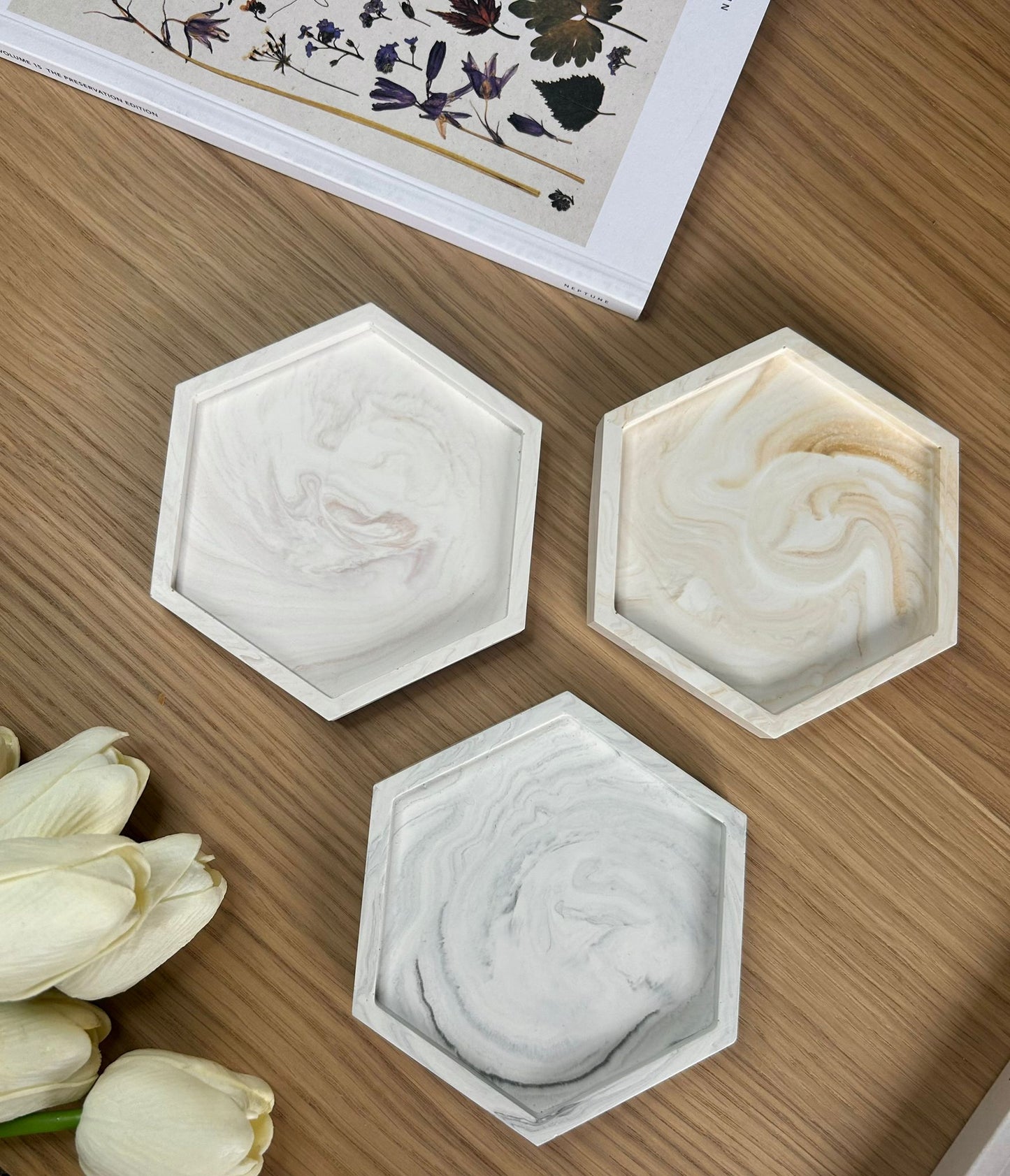 Handmade home accessories – hexagonal Jesmonite coasters in neutral marble tones, styled with a pressed flower book and tulips. Perfect for jewellery, candles or keys.