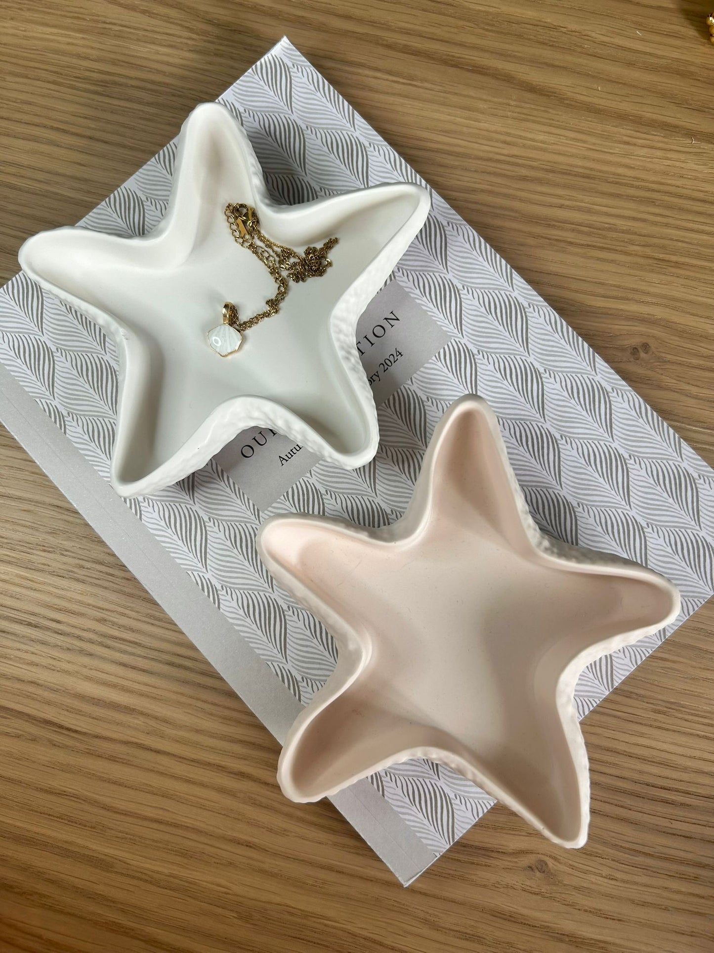 Flatlay of peach and white jesmonite star trinket dishes, each featuring a unique organic shape and styled with a gold necklace, perfect for minimalist and coastal-inspired interiors.