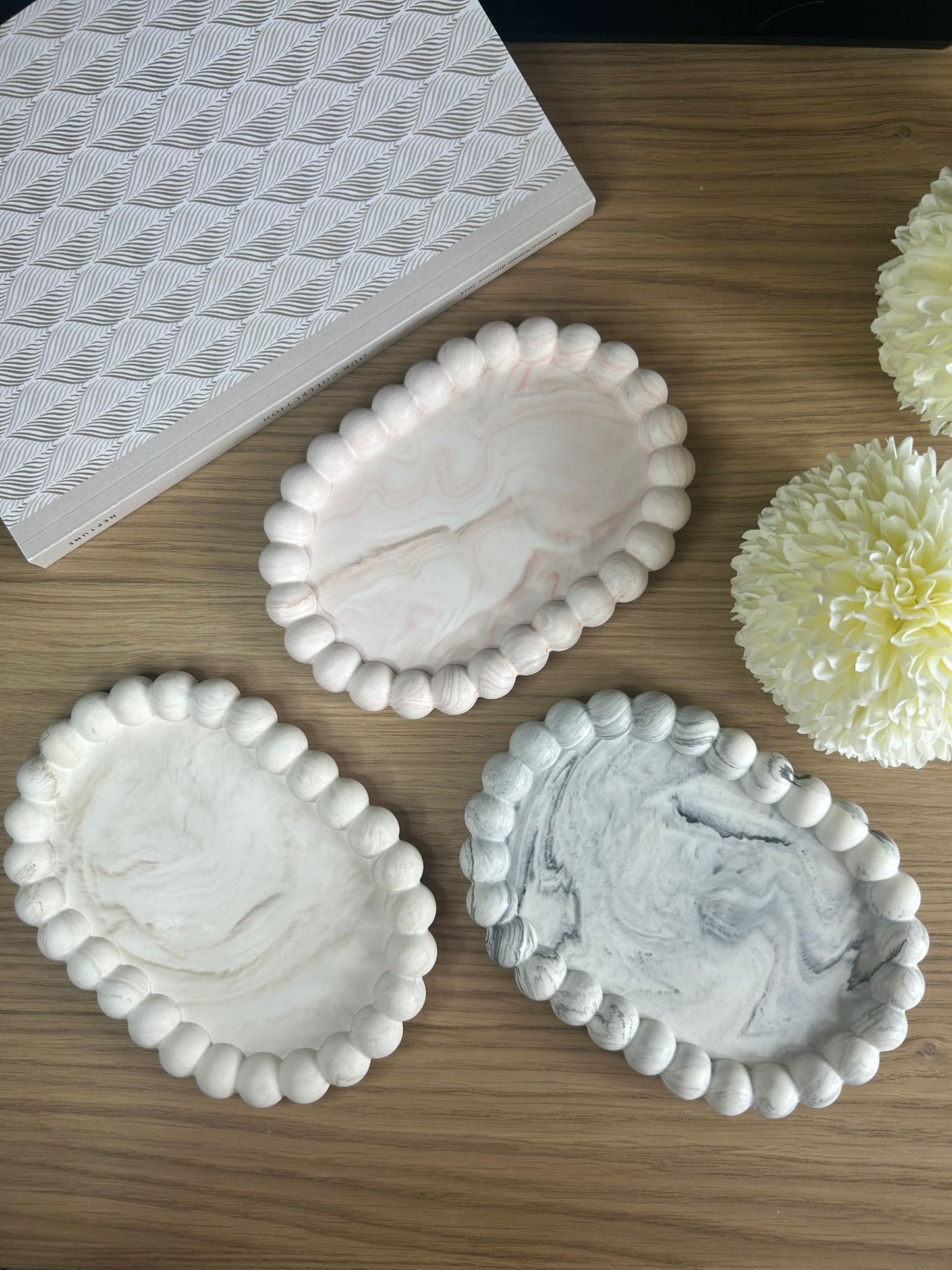 Set of three handmade Jesmonite trays with bubble-style edging, in cream, pink and grey marble finishes. Minimalist handmade home accessories for jewellery or décor.