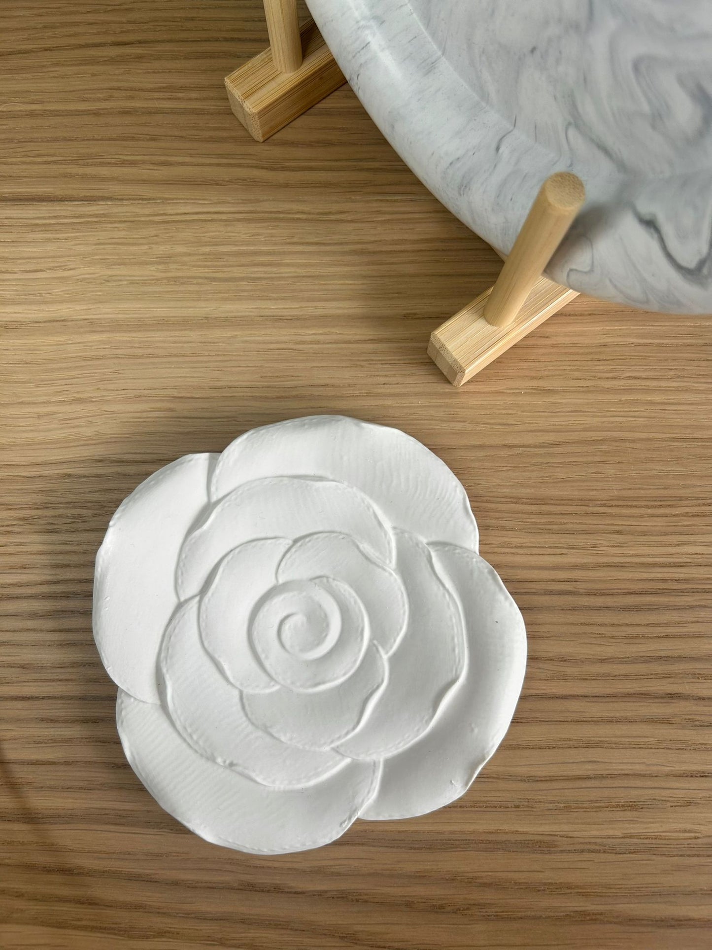 Handmade camellia flower tray in matte white Jesmonite, styled with a grey marbled tray on wooden stand – minimalist floral accessory.