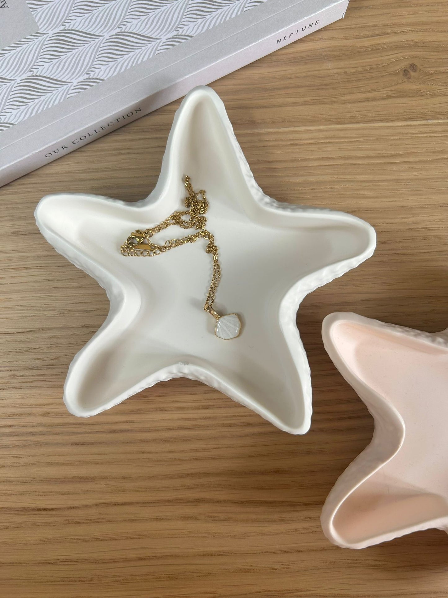 White star-shaped ceramic trinket dish styled with a delicate gold necklace and shell pendant, placed on a wooden surface for a natural, minimal aesthetic.