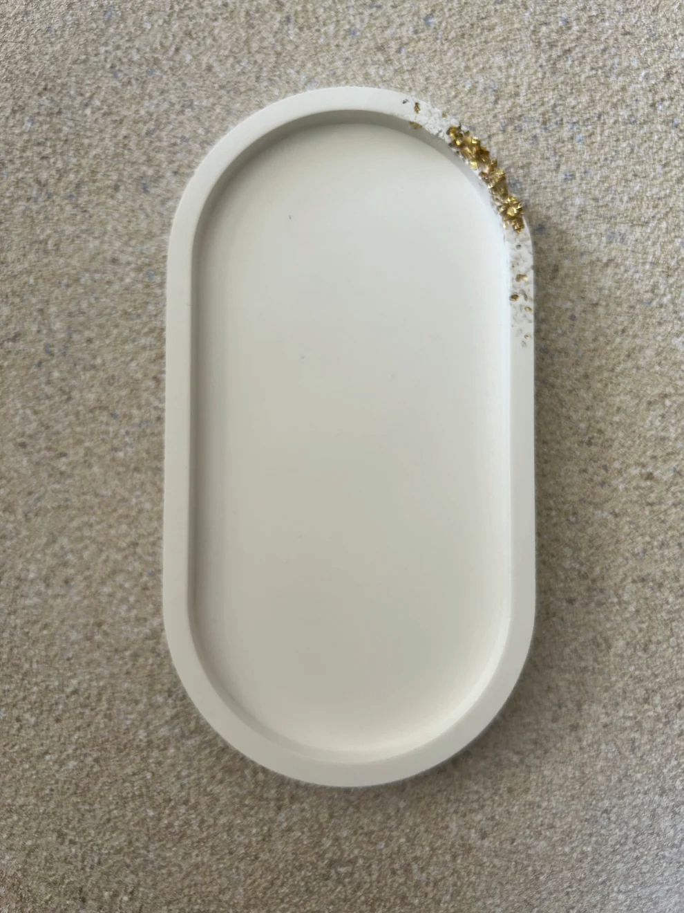 Handmade Home Accessories - vertical front shot of a plain white oval trinket tray with a subtle gold druzy style raw edge on the top right hand corner.