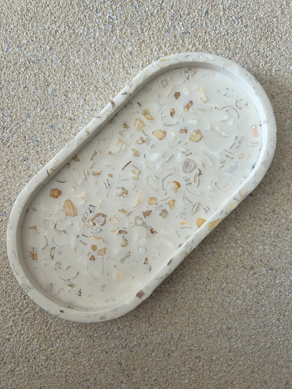 Handmade Home Accessories - a shot of the plain oval trinket tray that has crushed seashells in, on a natural sandstone backdrop.