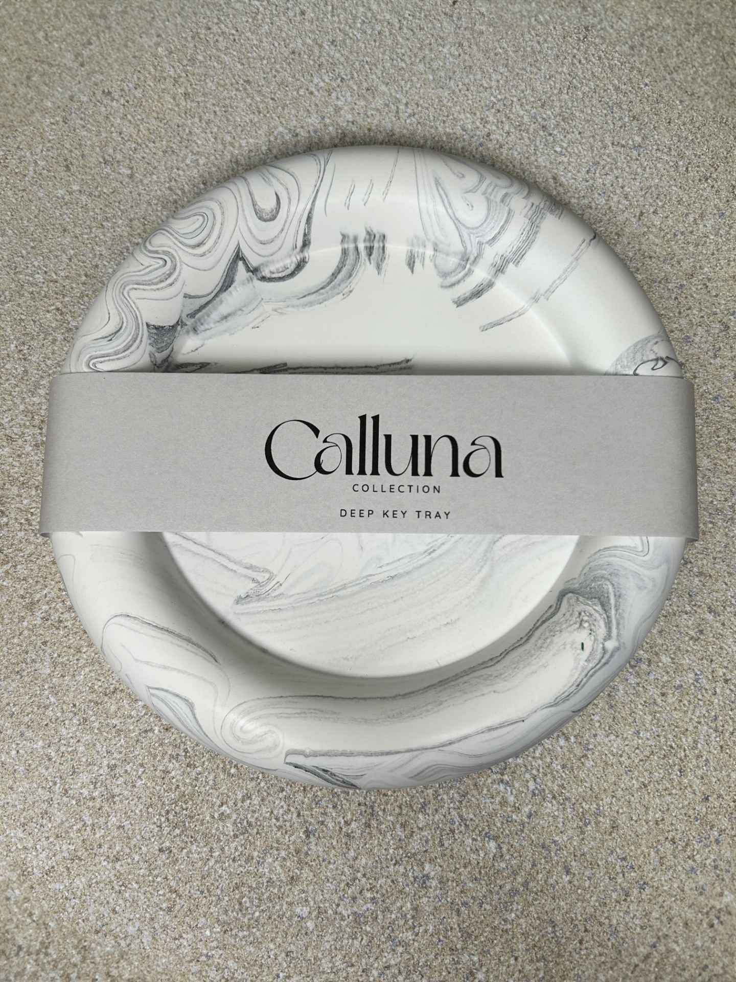 Handmade Home Accessories - A Black Marble chunky deep key tray with a belly band across saying the company name calluna collection. Photo is taken from a bird eye view to show how the product is packaged.