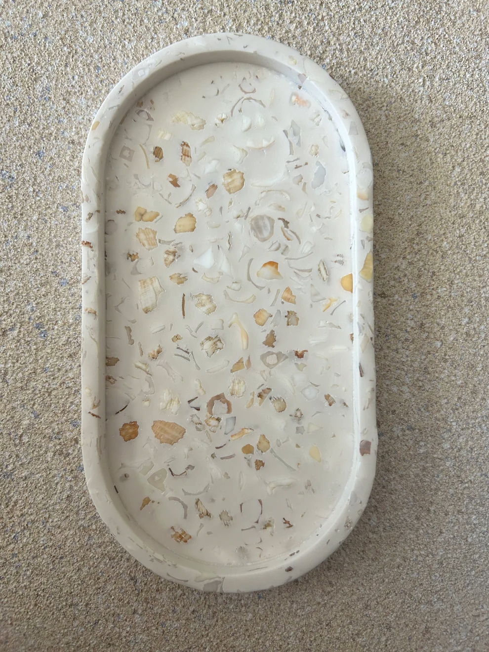 Handmade Home Accessories - A front on shot of the plain oval trinket tray. it is cream coloured, with a terrazzo design of real crushed seashells.