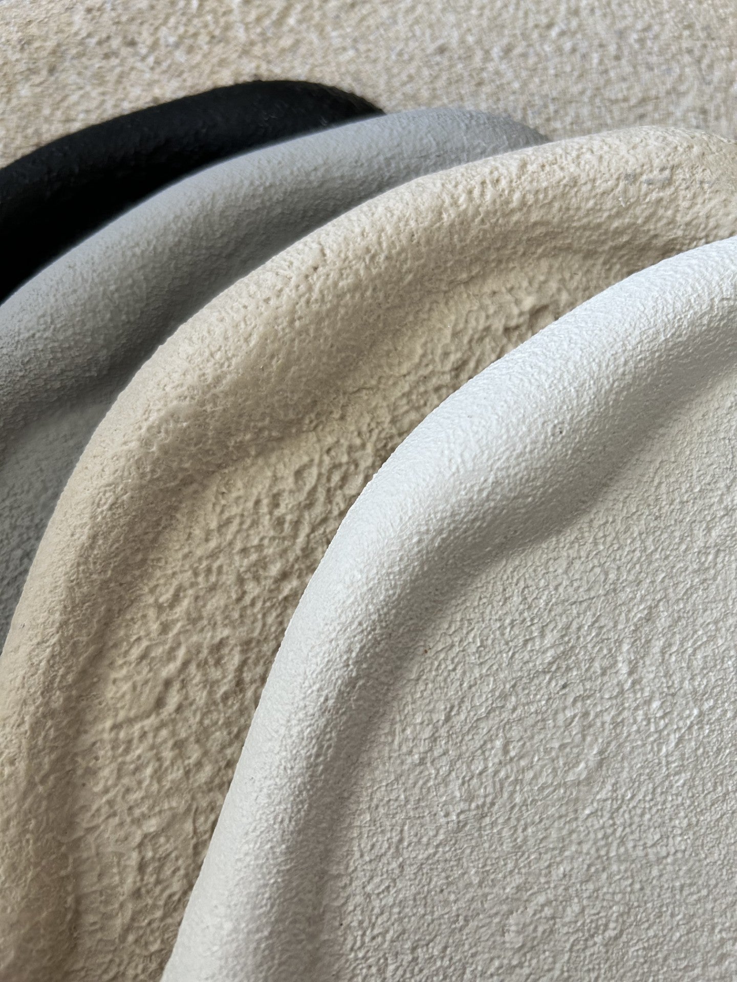 Handmade Home Accessories - Close up of four tectured pebble trays, showing the deifferent colours and textures in black, white, beige and grey.