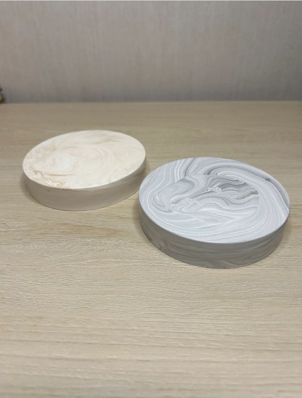 Handmade Home Accessories - two chunky marble coasters taken from an angled view to show the deoth of the coasters, one is grey marble the other is beige marble.