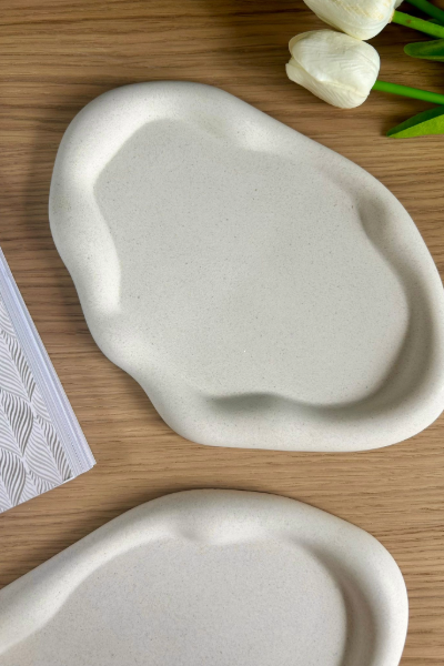 Organic-shaped handmade ceramic tray on a wooden surface, ideal for modern minimalist home decor and stylish accessory organisation.