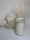 Handmade Solace Diffuser in a tall cylindrical Jesmonite vessel with soft marbled beige and stone grey tones, styled beside a matching Luna Arch Bookend on a minimalist surface for a cohesive, neutral display.