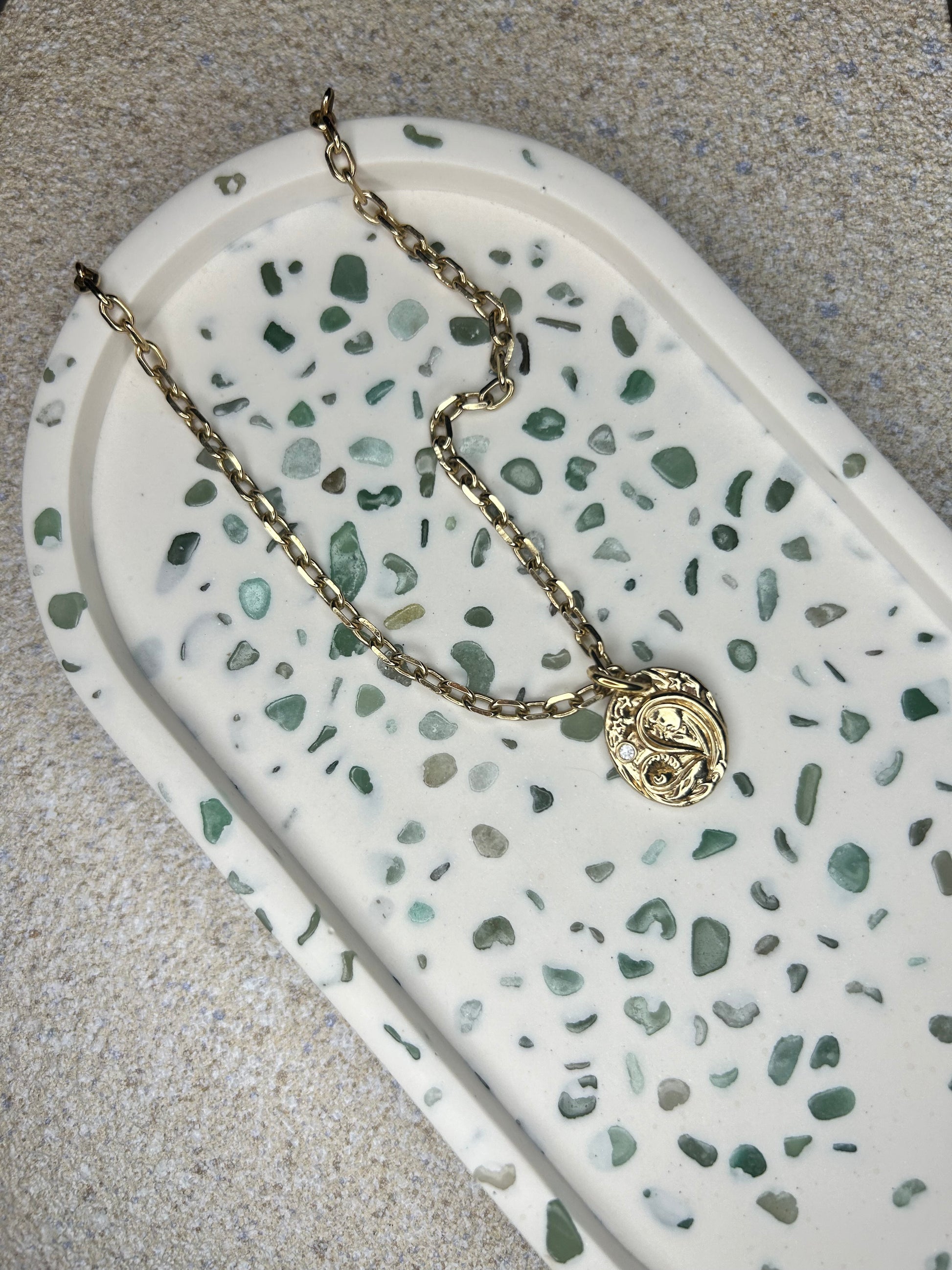 Handmade Home Accessories - Aventurine Quartz close up shot showing the shine on the gemstones. It also shows a shiny gold necklace stored on the tray and has a stone textured background.