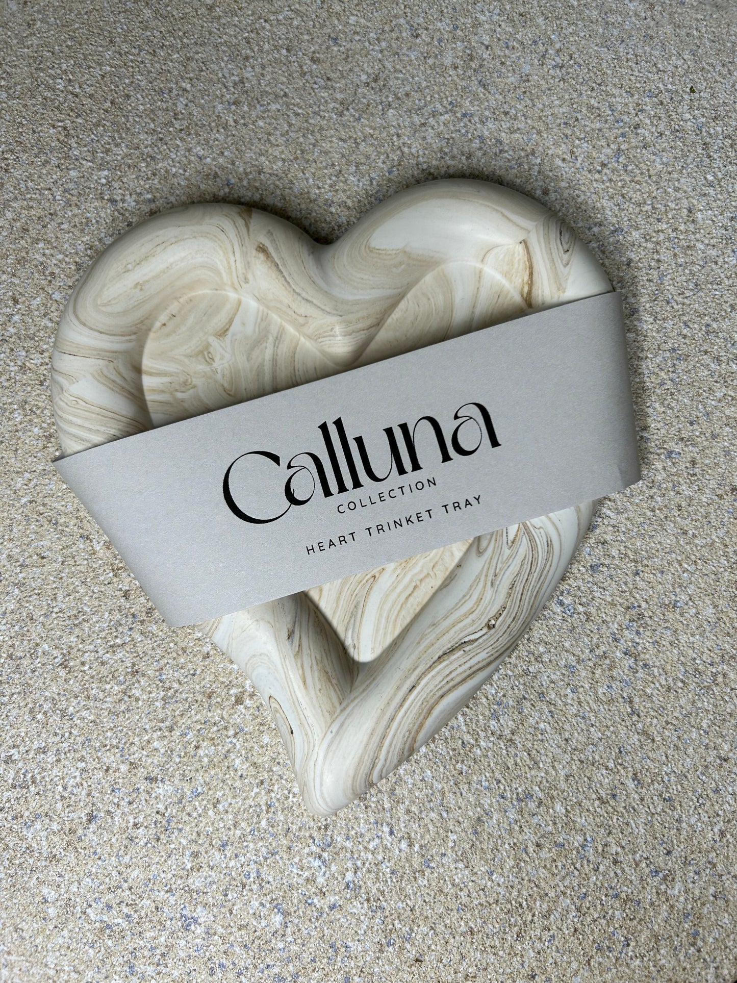 Handmade Home Accessories - A chunky brown marble heart shaped trinket tray with  a belly band saying Calluna Collection across the front, the photo is taken to show what packaging the product comes with.