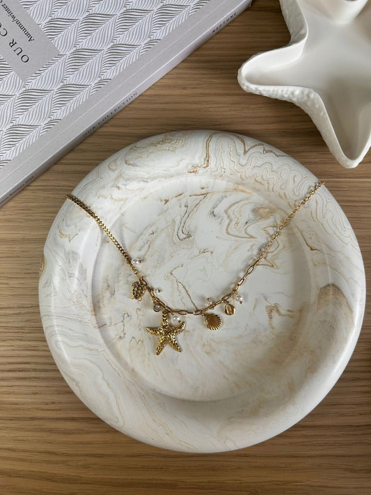 Marbled Jesmonite tray with gold sea-themed charm necklace – perfect handmade accessory for jewellery display.