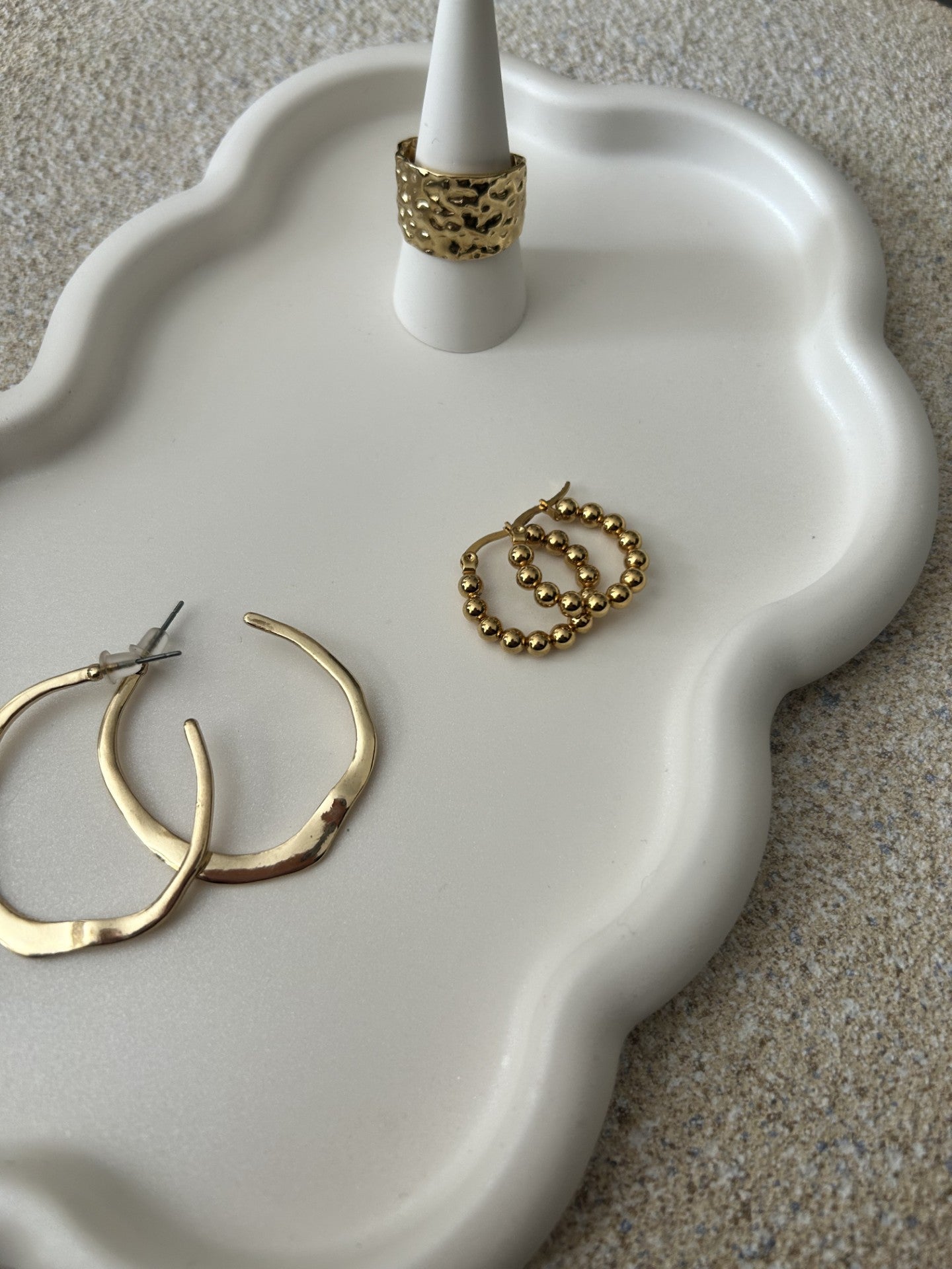 Handmade Home Accessories - Cloud Trinket Tray Close Up showing the white pear colour, and a ring holder showcasing a gold ring along with 2 pairs of gold earrings on a stone table backdrop.