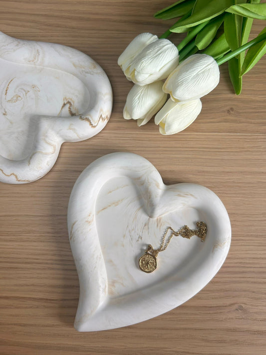 Set of handmade home accessories – two heart-shaped Jesmonite trays in a cream marble finish, styled with a necklace and white tulips. Elegant and eco-friendly.