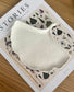 Handcrafted jesmonite tray shaped like a ginkgo leaf, styled on a floral-themed book. A sustainable, nature-inspired home accessory for conscious interiors.