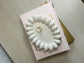 Handmade Home Accessories - A birds eye view shot of the daisy trinket tray on a bedrop of some books. Its oval shape with bubbles around the outside giving the appearance of a daisy.