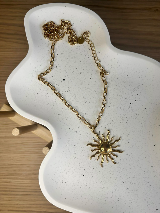 Gold sun necklace displayed on an organically shaped handmade Jesmonite tray with black speckles – elegant styling piece for minimalist interiors.