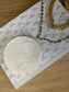 Creamy marbled coaster with soft neutral tones styled beside gold chain jewellery – minimal handcrafted home accessory.