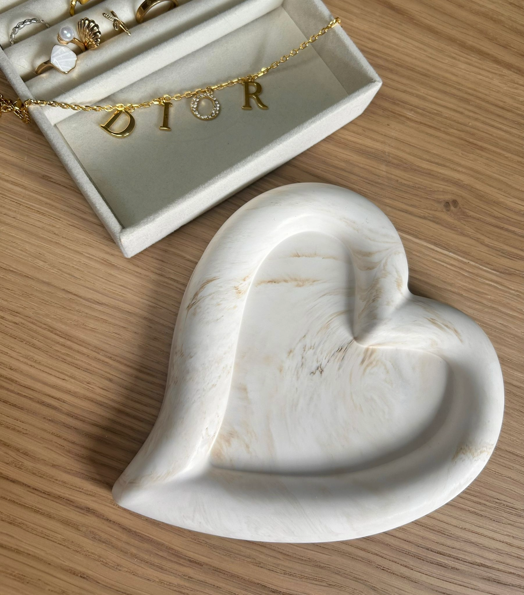 Handmade home accessory – heart-shaped Jesmonite tray with warm cream marbling, styled with a gold Dior bracelet. A minimalist jewellery dish crafted sustainably.