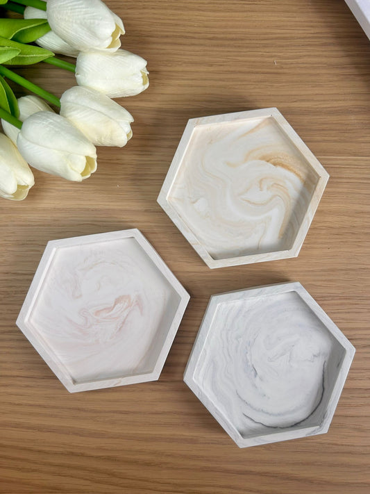 A trio of handcrafted Jesmonite trays in hexagonal shapes with soft marbled tones. Thoughtfully styled with tulips – ideal handmade home accessories for modern decor.