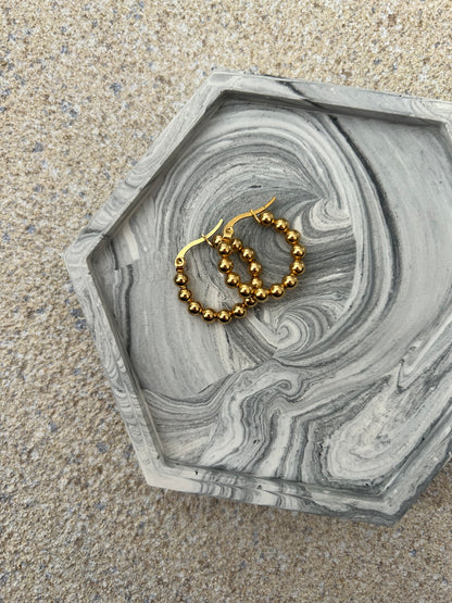 Handmade Home Accessories - One black marble style coaster, close up shot with gold hoop earrings to show versitility.