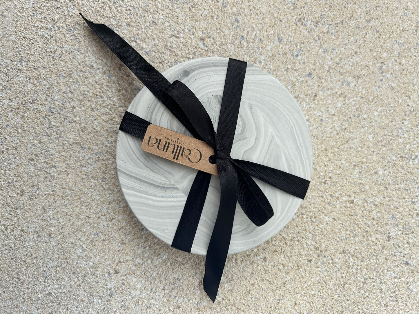 Handmade Home Accessories - One grey chunky coaster with a black ribbon around and a tag that says Calluna Collection.