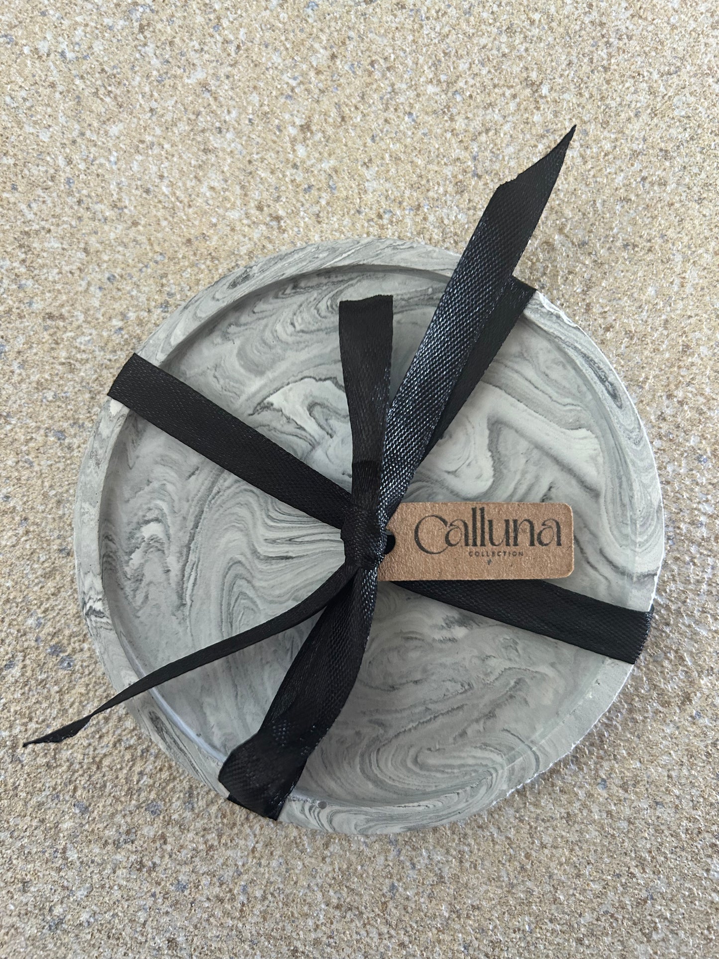 Handmade Home Accessories - A single black marble round coaster with a black ribbon tied around it with a brown tag that says Calluna Collection.