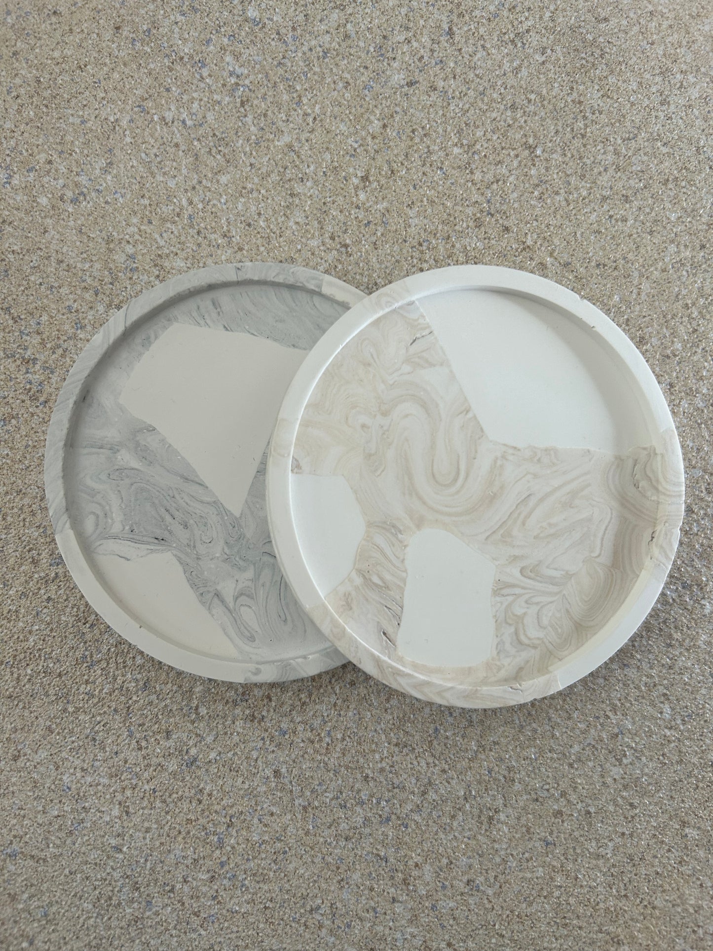 Handmade Home Accessories - A grey marble and white and a beige marble and white snap coaster on a natural stone background.