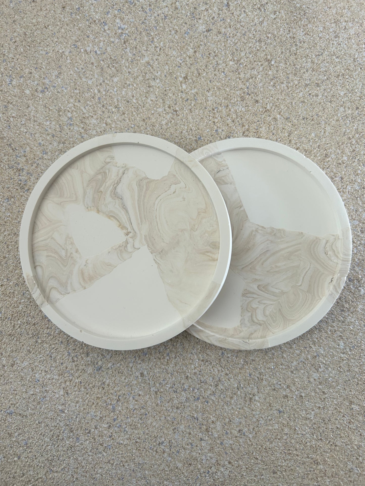 Handmade Home Accessories - two beige marble and white snap coasters on a antural stone background taken from a birds eye view.