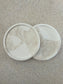 Handmade Home Accessories - two beige marble and white snap coasters on a antural stone background taken from a birds eye view.