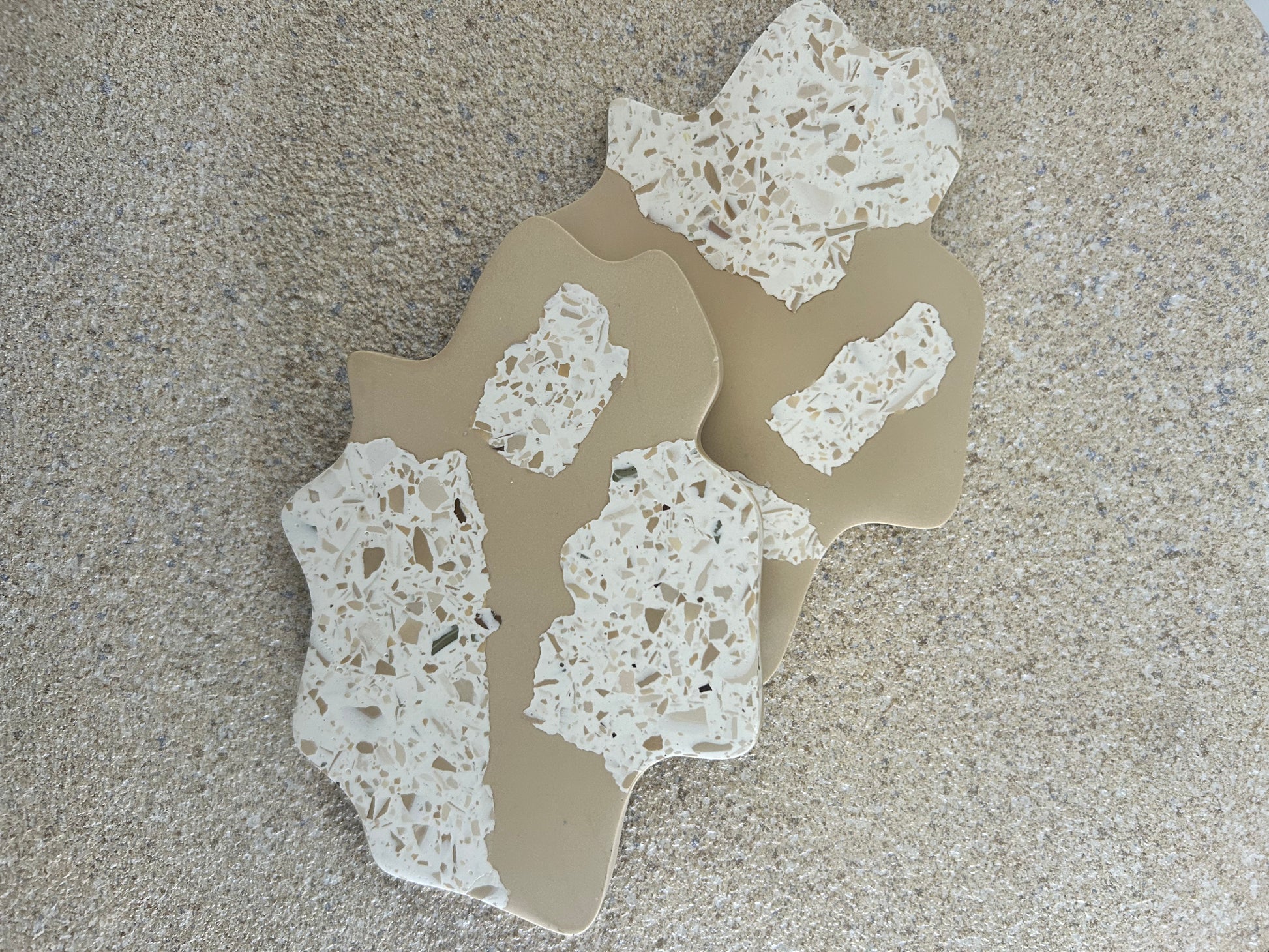 Handmade Home Accessories - A photo of two irregular coasters in a brown and white terrazzo design, with snap concepts.