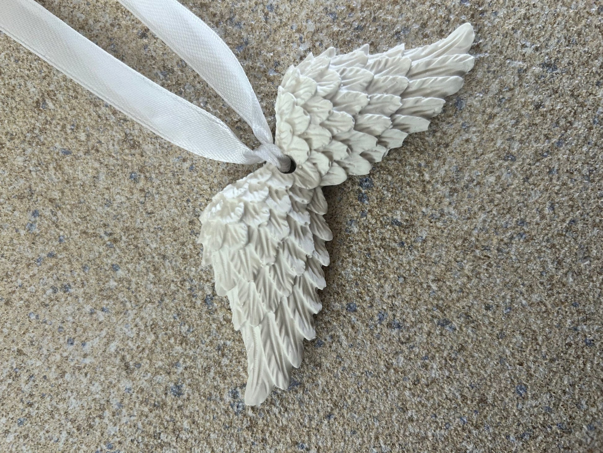 Handmade Home Accessories - a close up shot of white angel wings on a textured stone surface