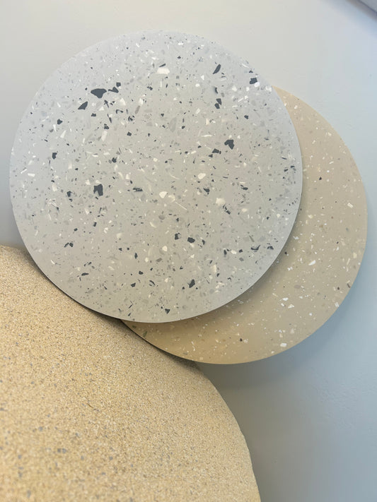 Handmade Home Accessories - A Large Terrazzo style display plate, perched on a stone table. there is one in a grey style and one in beige style.