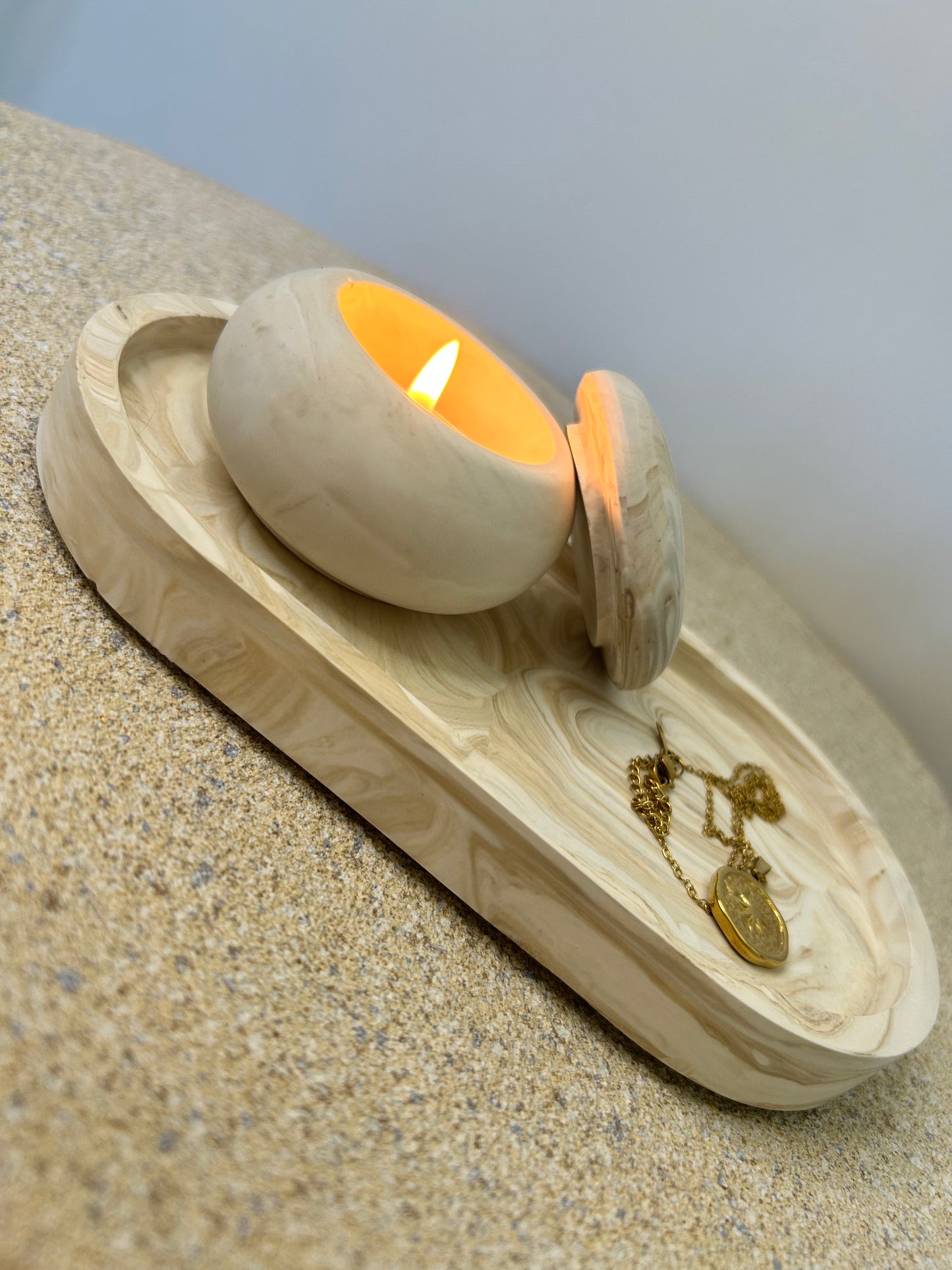 Handmade Home Accessories - a beige marble mushroom pot with a lit tealight in on a beige marble trinket tray that has a gold coin necklace on