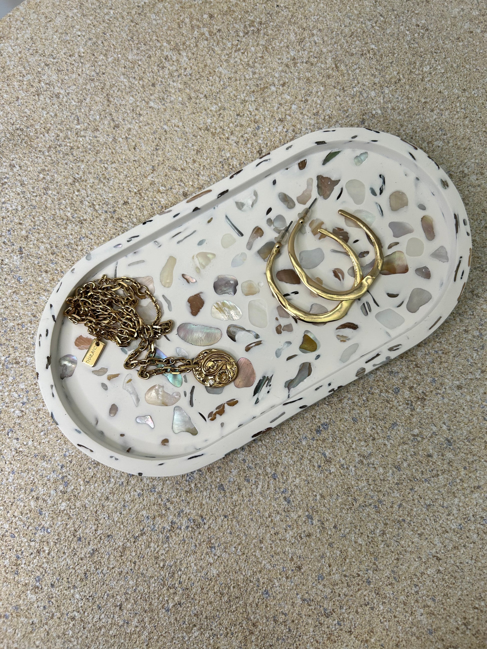 Handmade Home Accessories - an oval trinket tray with shiny pebble details with a gold necklace and gold hoops displayed.