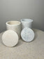 Handmade Home Accessories - a picture of two storage pots with the lids displayed infront of them, one is beige marble and the other grey marble