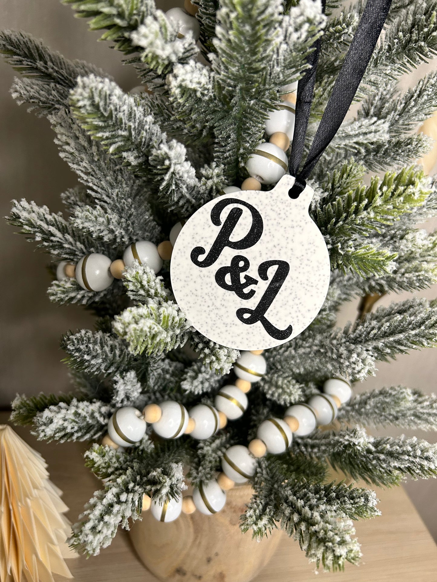 Handmade Christmas Decor - Sparkling initial hanging ornament with black P&L on, hanging on a Christmas tree.