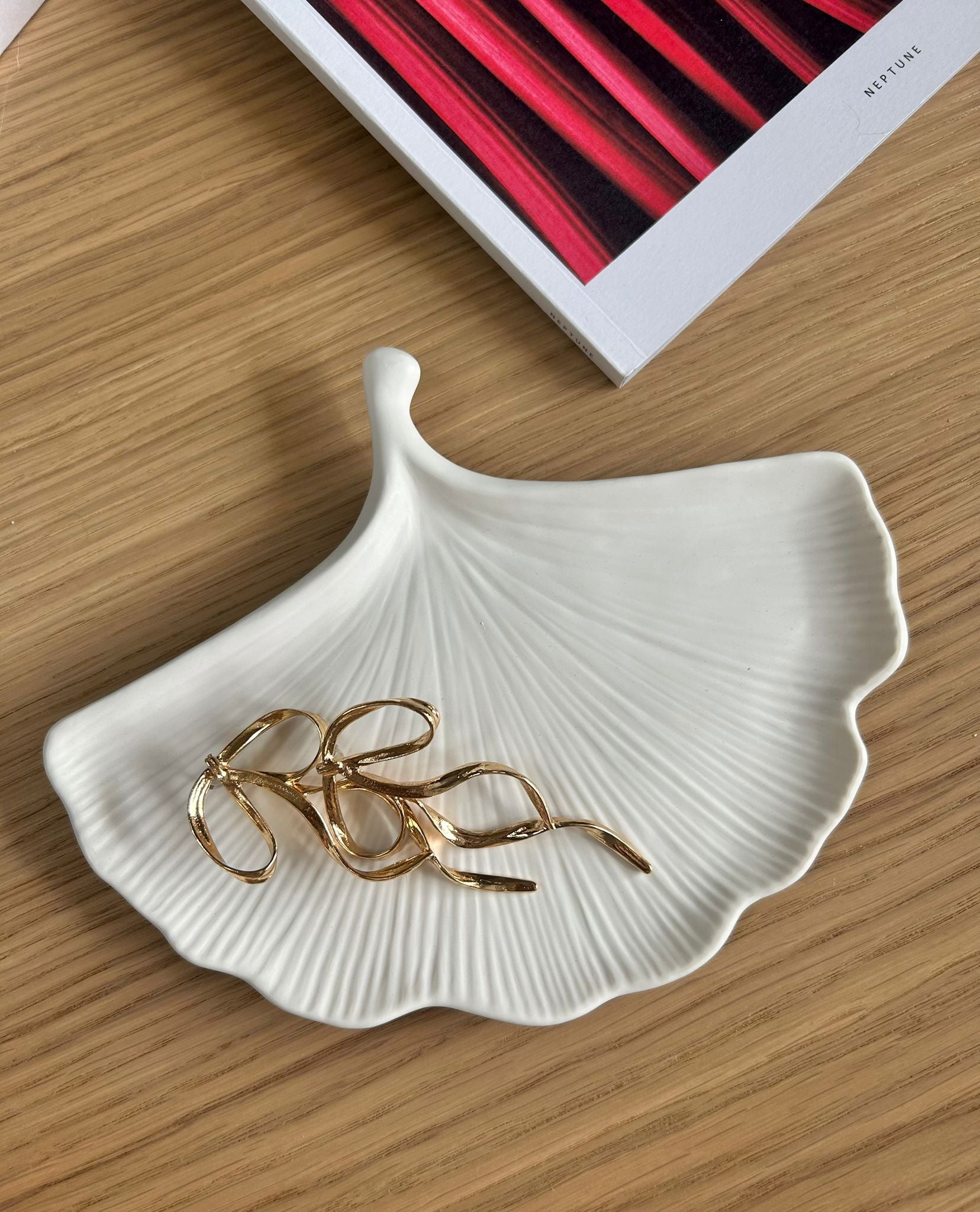 Minimalist jesmonite leaf tray used as a jewellery holder, styled with gold bow earrings and modern table decor – a refined handmade home accessory.