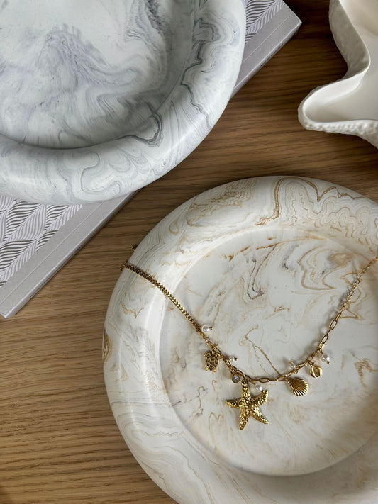 Two marbled decorative trays with gold starfish necklace – bespoke handmade home accessories with coastal tones.
