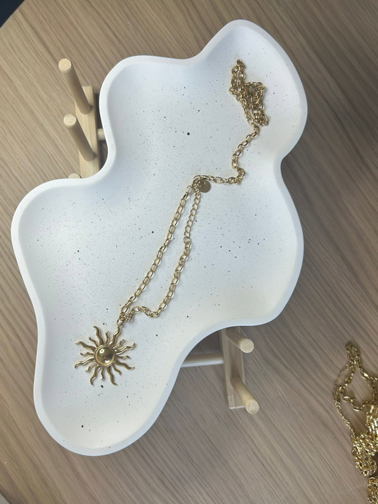 White speckled Jesmonite tray in an abstract organic shape, styled with a gold sun pendant – artistic handmade tray for jewellery or décor.