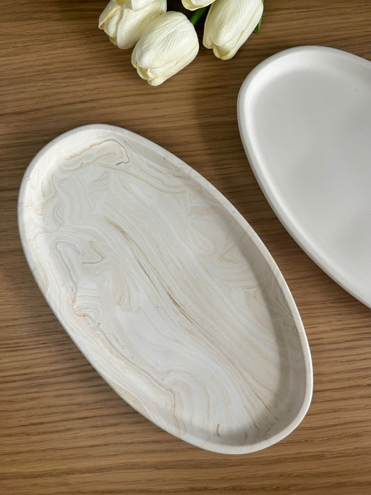 Handmade oval trinket dish in a marbled cream finish with organic swirls, styled with white tulips on a wooden surface, ideal for home accessories.