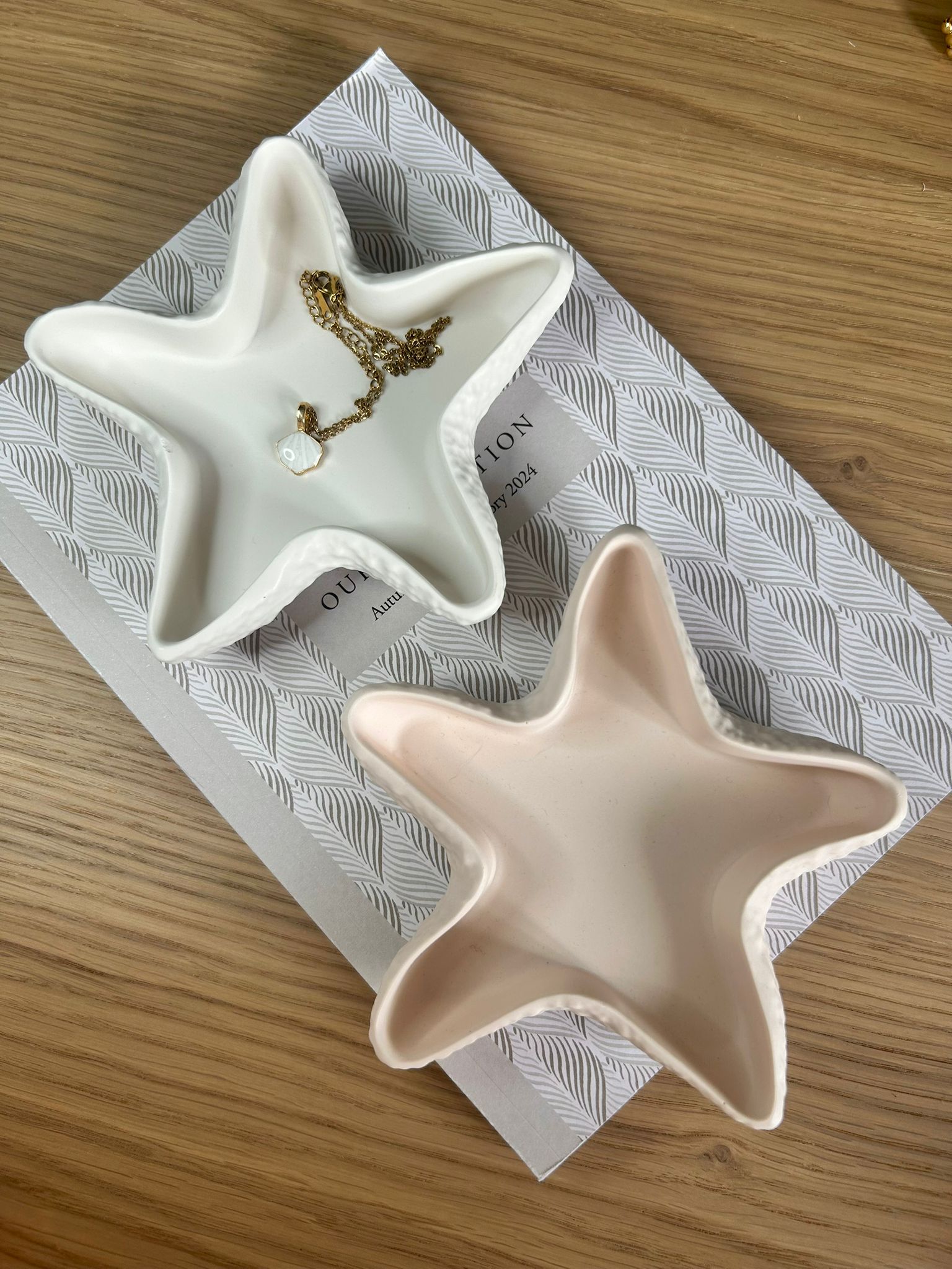 Flatlay of peach and white jesmonite star trinket dishes, each featuring a unique organic shape and styled with a gold necklace, perfect for minimalist and coastal-inspired interiors.