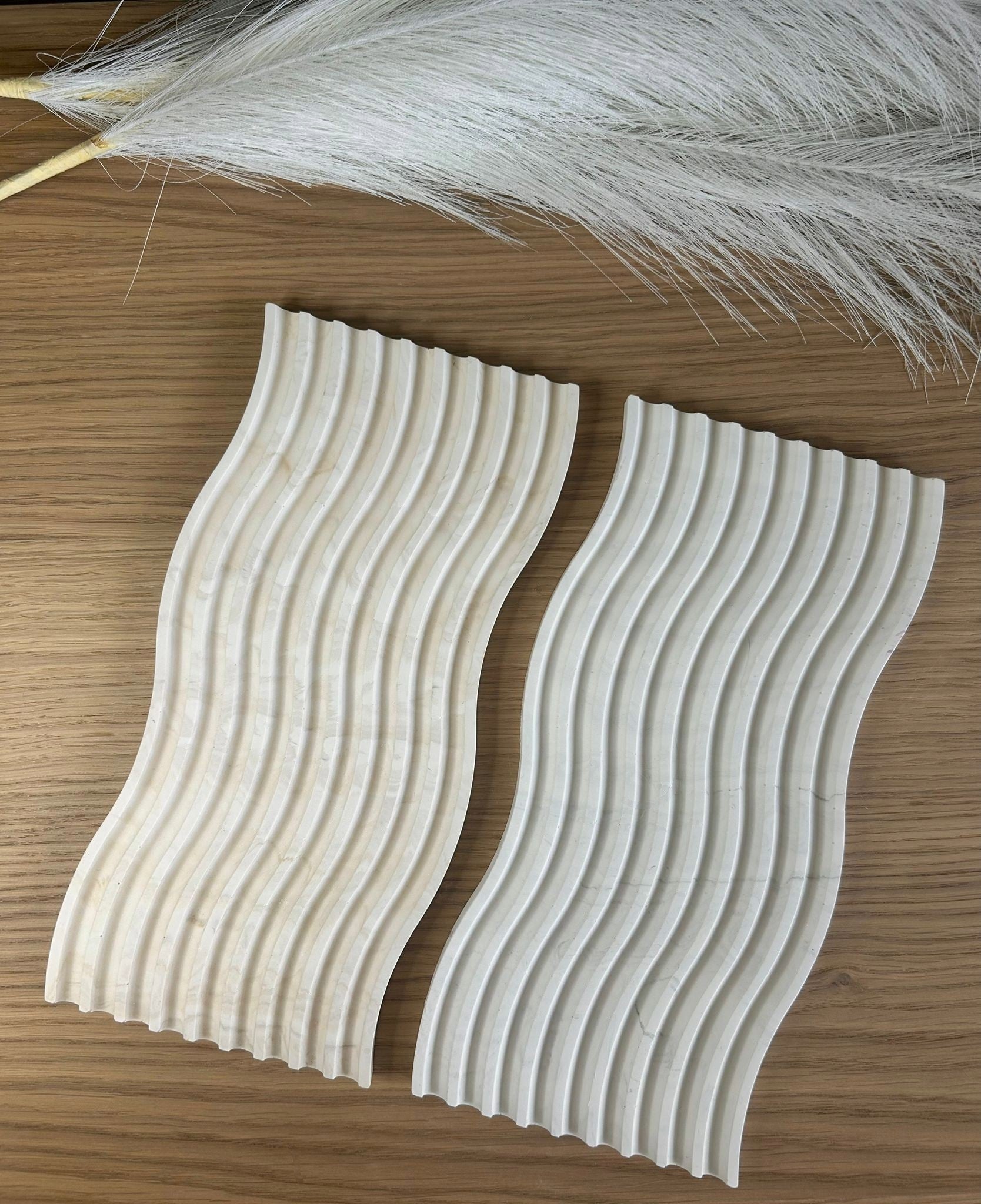 Pair of ripple-effect Jesmonite trays in a soft off-white marble finish, styled with pampas grass – organic handmade home accessories.