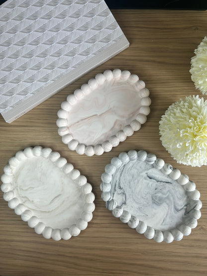 Set of three handmade Jesmonite trays with bubble-style edging, in cream, pink and grey marble finishes. Minimalist handmade home accessories for jewellery or décor.