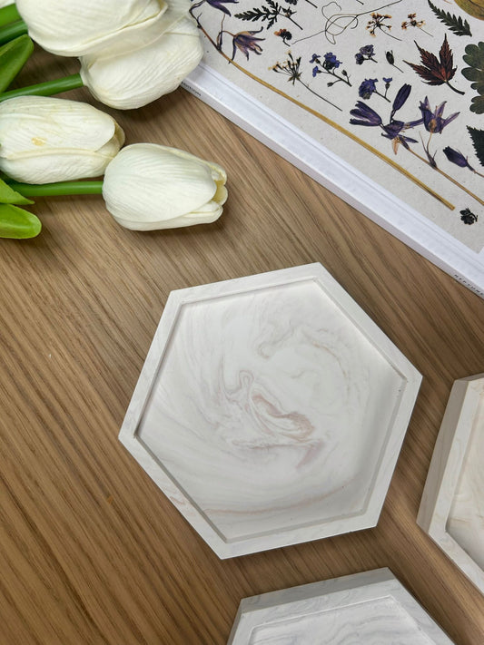 Close-up of a single hexagonal Jesmonite coaster with soft blush marble swirls. A minimalist, sustainable home accessory for jewellery or trinkets.