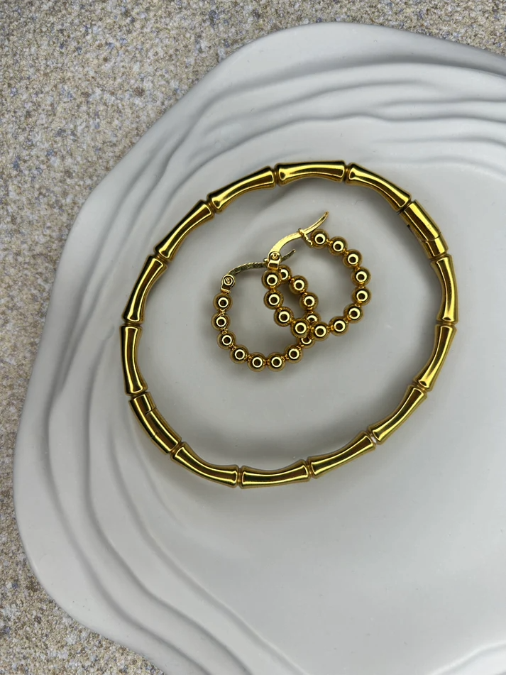 Handmade Home Accessories - Close up shot of the ripple trinket tray in grey, showing the ripple detail and a pair of gold hoops and a gold wishbone bracelet.