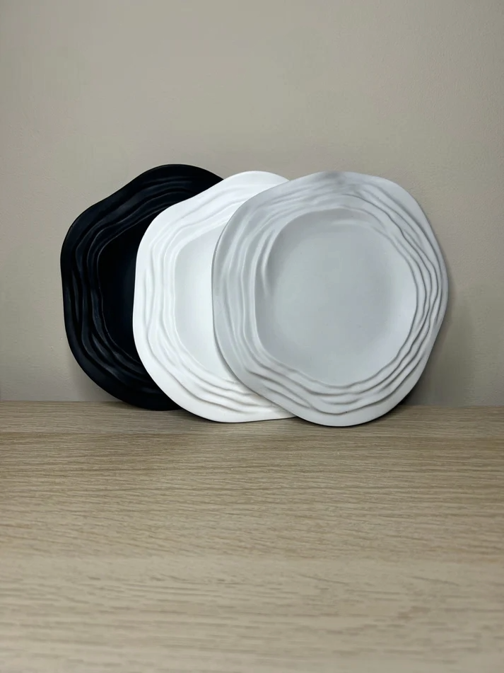 Handmade Home Accessories - A photo of three trinket trays, propped against a light brown wall, settled on a piece of oak. They are black, then white, then grey.