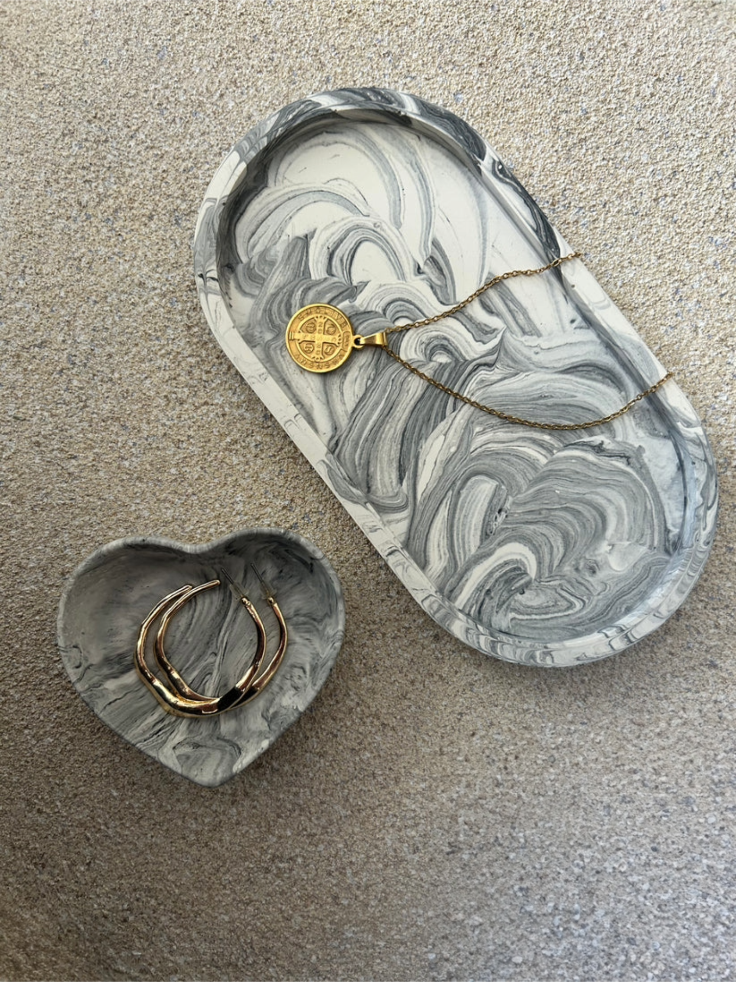 Handmade Home Accessories - A black marble, oval trinket dish and a matching black marble heart disj, with gold hoop earring and a gold necklace used for display.